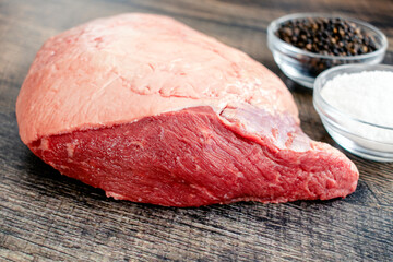 Ingredients for Grilled Picanha Steaks: Whole beef picanha with kosher salt and black pepper on a wood background