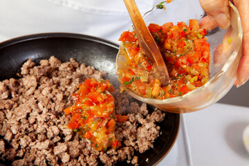 Preparation of ground beef with the traditional Colombian hogao or criollo sauce (salsa criolla) made of onion, tomato, peppers and cilantro