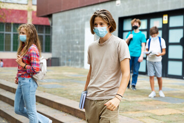 Portrait of teenager boy in protective mask going to school lessons on sunny summer day