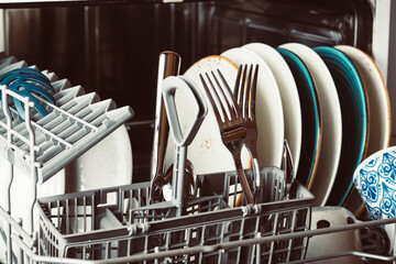 Clean dishes in an open dishwasher in a home kitchen close-up