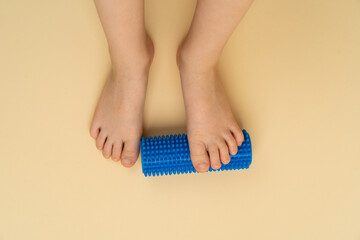 blue needle roller for massage and physiotherapy on a beige background with the image of a child's...