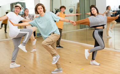 Interested modern teen boys and girls practicing dynamic boogie-woogie in pairs during group class...