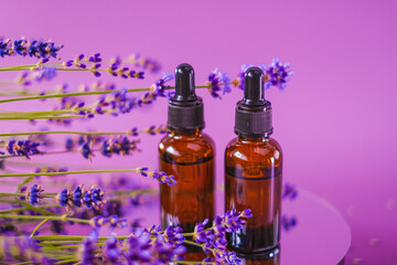 Obraz na płótnie Canvas Lavender essential oil.Aromatherapy and massage.Brown glass bottles oil set and lavender flowers on a purple background.aroma of lavender.Essence with lavender