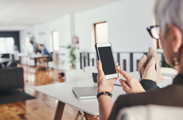 Connected and comfortable. Rearview shot of an unrecognizable mature businesswoman checking her text messages while sitting in her office.