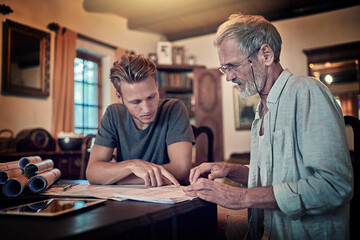 These great minds think alike. Shot of a father and his son working on a design for their family business at home.