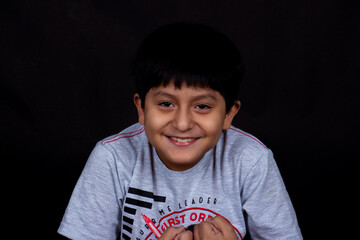 retrato de niño sonriendo con camiseta gris en estudio fotográfico con fondo negro