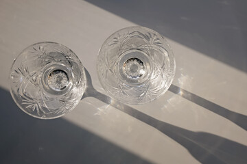 Two crystal glasses on the white table in natural sunlight