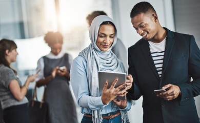 Just another busy day in the office. Shot of a group of young cheerful businesspeople browsing on...