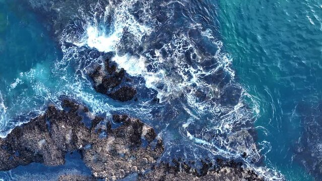 Aerial view of waves hitting the rock in sea. Top down view of waves and clifs. Aerial view of waves and some of rocks.