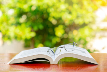 Close-Up of eyeglasses with open book On Table in front yard.