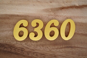 Golden Arabic numerals on a real brown and white wooden floor number 6360