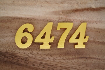 Golden Arabic numerals on a real brown and white wooden floor number 6474