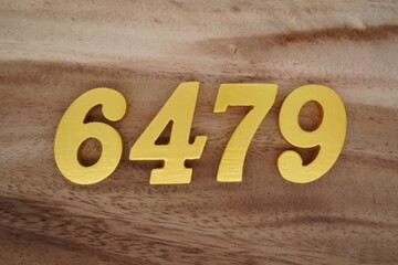 Golden Arabic numerals on a real brown and white wooden floor number 6479