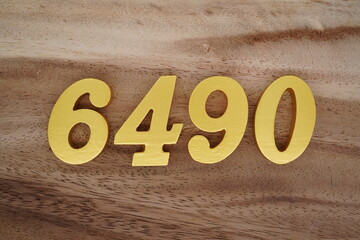 Golden Arabic numerals on a real brown and white wooden floor number 6490