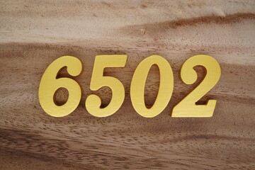 Golden Arabic numerals on a real brown and white wooden floor number 6502