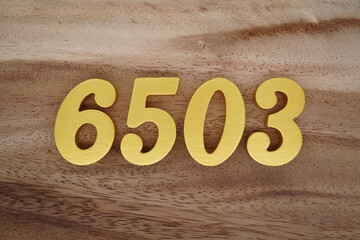 Golden Arabic numerals on a real brown and white wooden floor number 6503