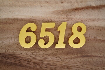 Golden Arabic numerals on a real brown and white wooden floor number 6518
