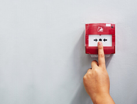 Activating The Alarm. Cropped Shot Of A Person Pressing A Fire Alarm On A Wall.