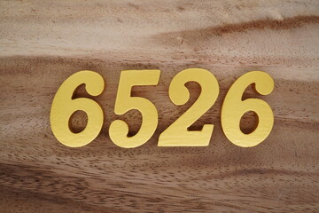 Golden Arabic numerals on a real brown and white wooden floor number 6526