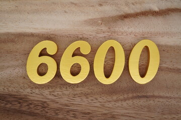Golden Arabic numerals on a real brown and white wooden floor number 6600