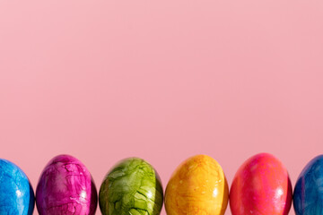 Easter eggs arranged in a single row on a solid pink background. Easter.