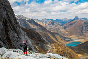 Hiker on a mountain in the Peruvian Andes, in the background a beautiful lake and blue sky.