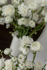 Composition of white flowers in a vase on a chest of drawers
