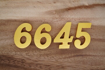 Golden Arabic numerals on a real brown and white wooden floor number 6645