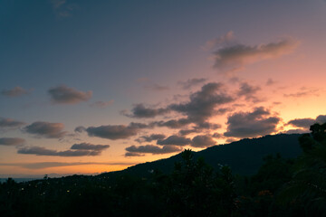 Colorful cloudy sky over trees and mountains at sunset 