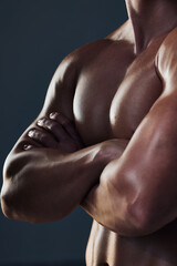 Fototapeta na wymiar Muscles on muscles. Closeup shot of an unrecognizable and athletic young mans chest while he poses arms folded in studio against a dark background.