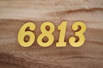 Golden Arabic numerals on a real brown and white wooden floor number 6813
