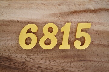 Golden Arabic numerals on a real brown and white wooden floor number 6815