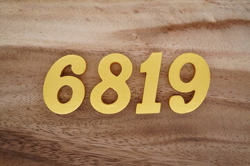 Golden Arabic numerals on a real brown and white wooden floor number 6819