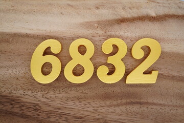 Golden Arabic numerals on a real brown and white wooden floor number 6832