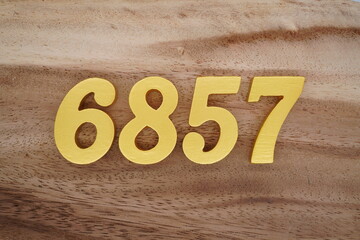 Golden Arabic numerals on a real brown and white wooden floor number 6857