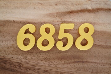 Golden Arabic numerals on a real brown and white wooden floor number 6858