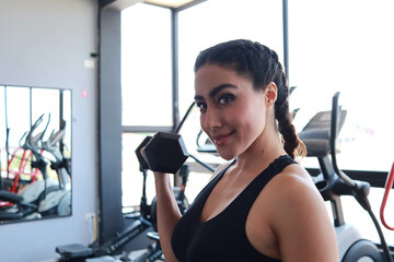 Fototapeta na wymiar beautiful girl smiling in the gym doing arm exercises