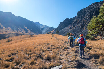 Fototapeta na wymiar Group of hikers walking towards the mountain in the middle of a landscape with grass and rocky elevations on a sunny day in the Nevado de Toluca in Mexico