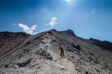 horizontal shot of mountaineers walking towards the summit of a rocky mountain on a sunny day in the Nevado de Toluca in Mexico