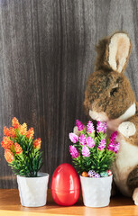 Vertical view of a bunny next to two decorative pots with small eggs and a red one.