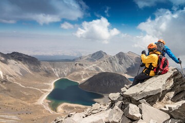 two hikers admiring the landscape of a crater and its volcanic lakes in the Nevado de Toluca in...