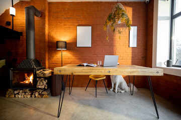 Living room interior in lofft style with wooden table and fireplace at home. White dog lying on the floor. Cozy home interior