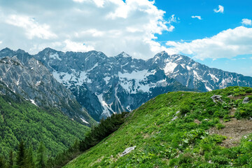 Fototapeta na wymiar Panoramic view from the summit of Goli Vrh on rocky sharp mountains of Kamnik Savinja Alps in Carinthia, border Austria and Slovenia. Green spring meadow in Vellacher Kotschna. Mountaineering. Freedom