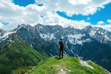 Fototapeta na wymiar Man with backpack walking on hiking path with scenic view on mountains Kamnik Savinja Alps in Carinthia, border Slovenia Austria. Velika Baba, Vellacher Kotschna. Mountaineering. Freedom concept
