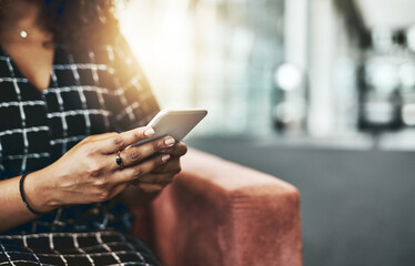 Good businesswomen are always reachable. Cropped shot of an unrecognizable businesswoman using a smartphone while sitting on a couch in a modern office.