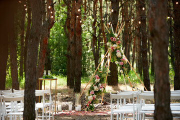 Beautiful bohemian tipi arch decoration on outdoor wedding ceremony venue in pine forest with...