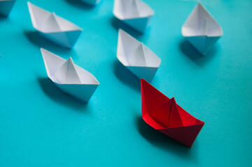 Leadership Concept - Red color paper ship origami leading the rest of the white paper ship on blue cover background. Copy space concept - obrazy, fototapety, plakaty