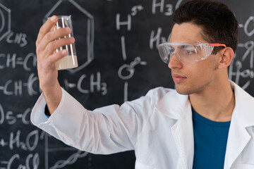 arabic chemist conducting experiment mixing liquids in flask, laboratory assistant in goggles showing chemical reaction in lesson, chemistry science