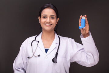 Portrait of young doctor woman showing inhaler 