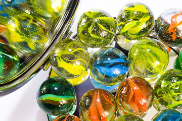 Colored glass marbles on a two-sided pocket mirror. Mirror reflections of colorful marbles in selective focus. Different dimensions, different lives, differences concept.